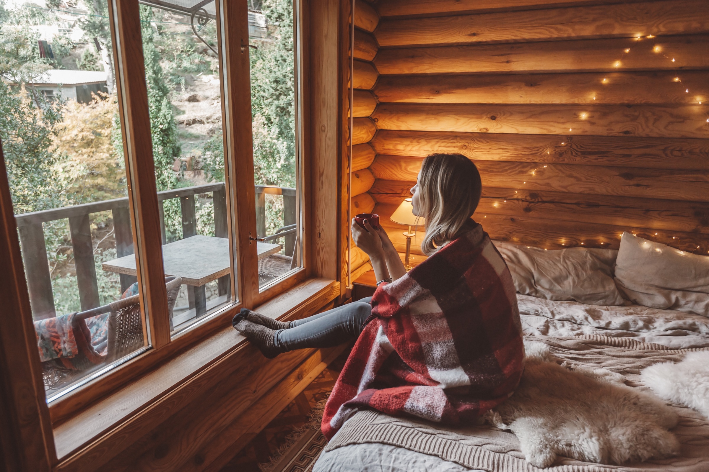 Woman relaxing with a hot drink in a cottage surrounded by nature in Quebec