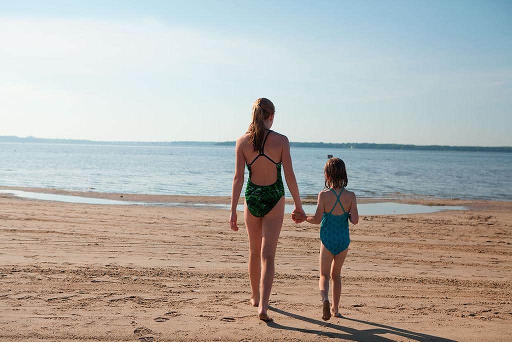 Adult and child walking toward the water at Oka Beach in the Laurentians