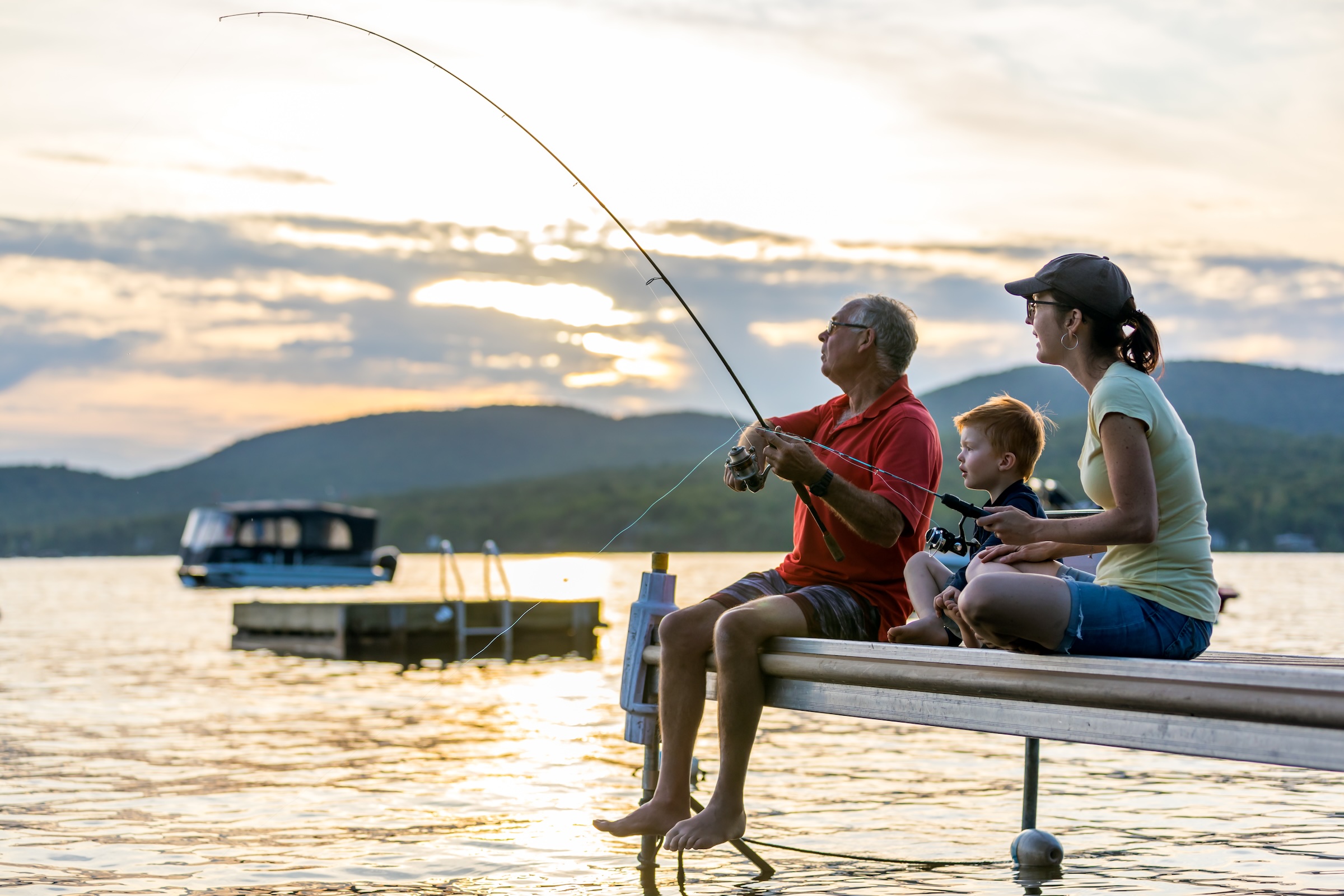 Family fishing together from a dock on a Quebec lake during a cottage getaway.
