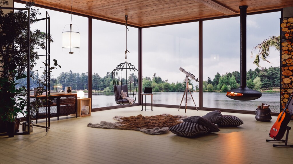Bright lakefront cottage living room in Quebec with large windows, a suspended fireplace and a view of the water.
