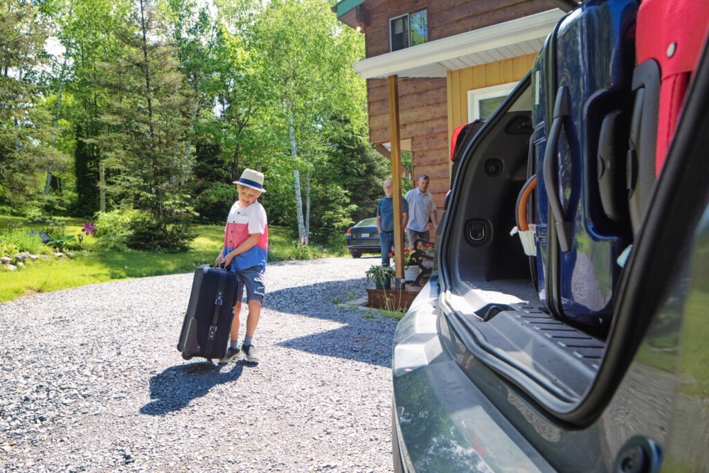 Family arriving at an Ontario cottage with luggage for a weekend getaway